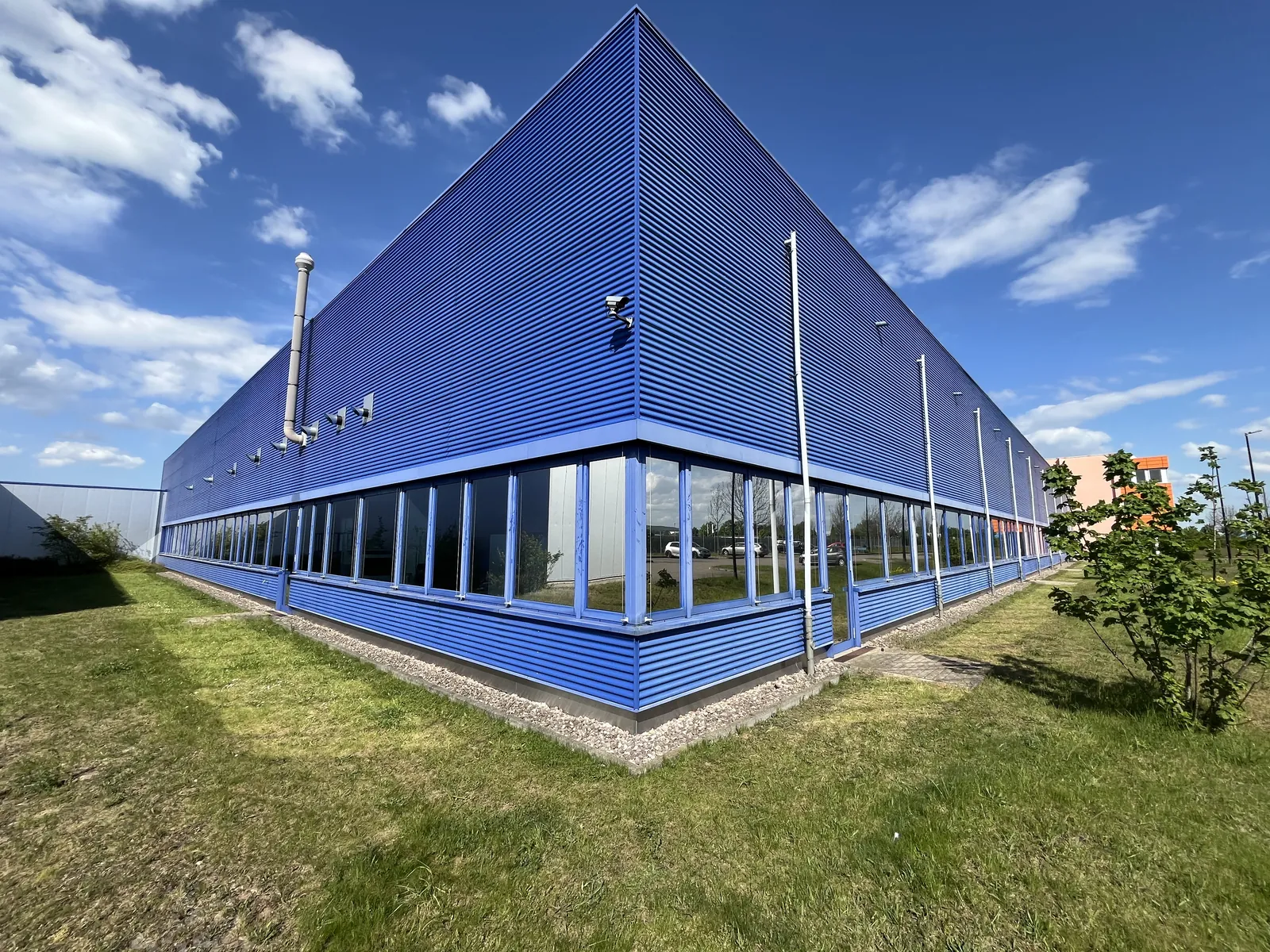 Blaue Halle mit getönter Fensterfront.