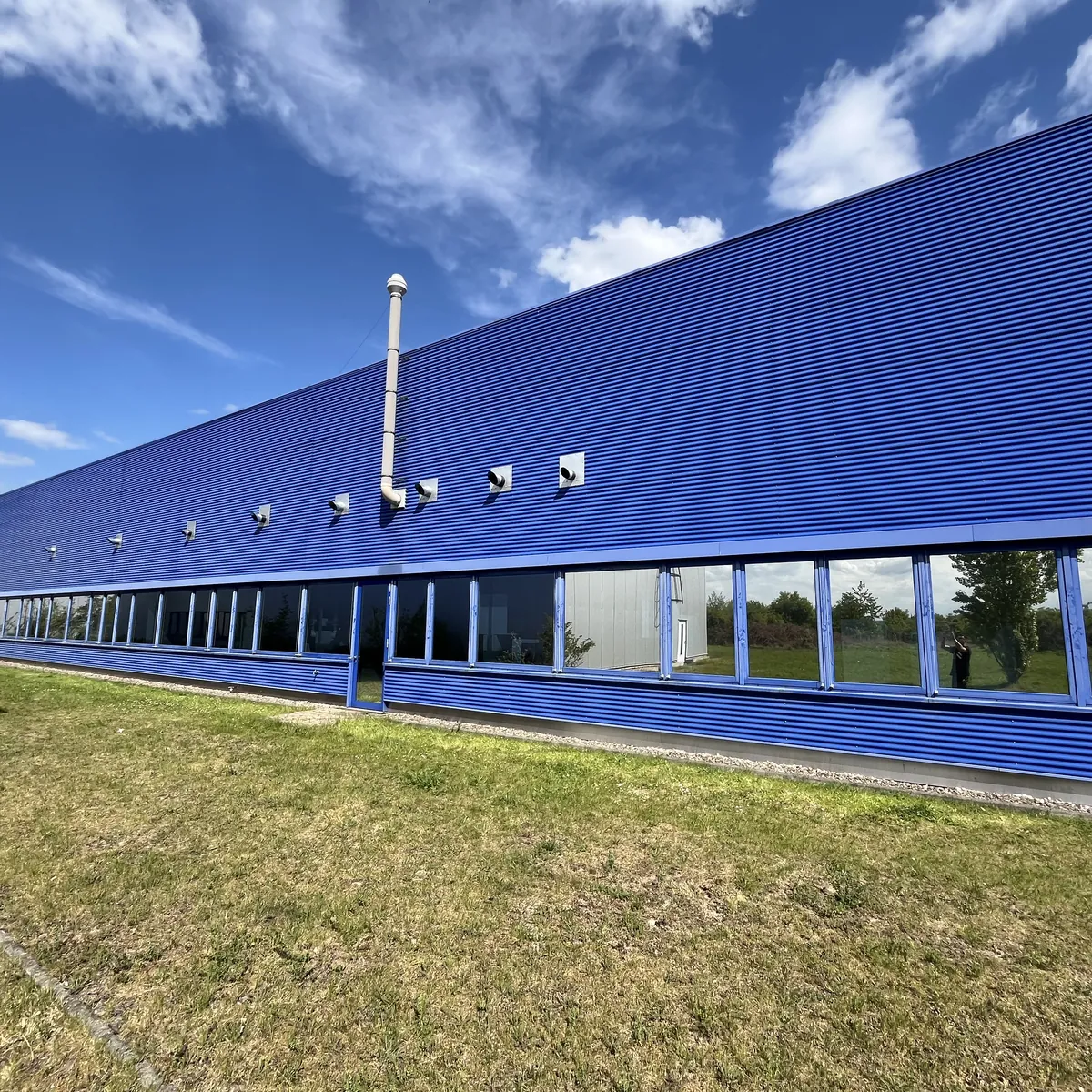 Blaue Halle mit getönter Fensterfront.