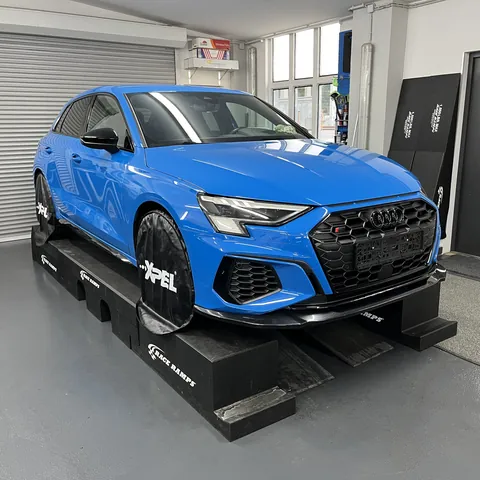 Blauer Audi RS3 auf Auffahrrampen in der Halle, 2022